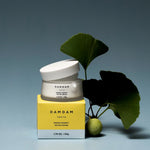 DAMDAM Ginkgo Bouncy Water Cream jar and yellow box beside fresh ginkgo leaves
