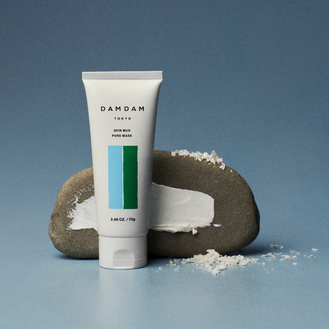 DAMDAM Skin Mud Pure Mask tube beside a stone and kaolin clay powder