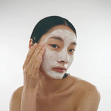 Model wearing DAMDAM Skin Mud Pure Mask as a smooth layer of clay on her face