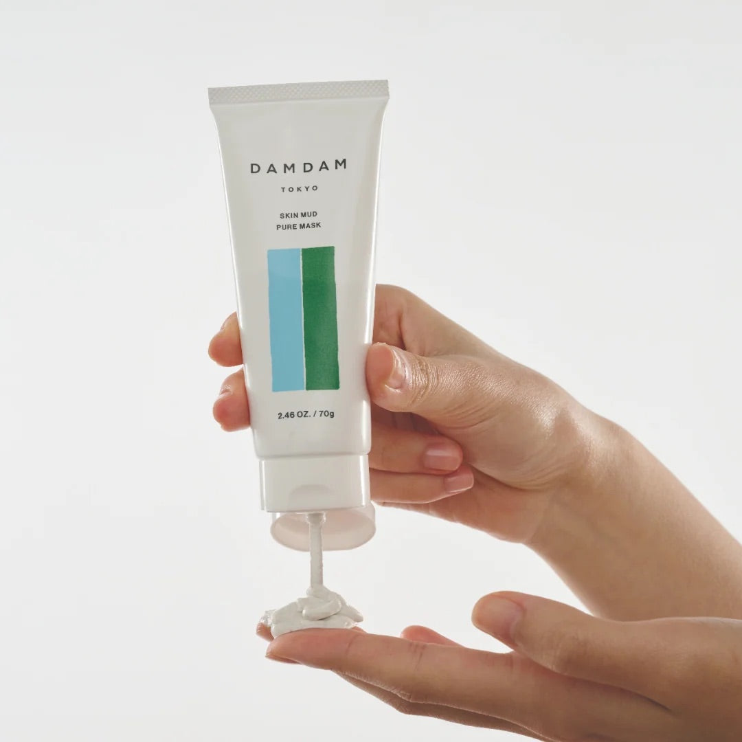 DAMDAM Skin Mud Pure Mask squeezed from the tube onto a fingertip, showing its creamy clay texture