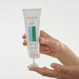 DAMDAM Skin Mud Pure Mask squeezed from the tube onto a fingertip, showing its creamy clay texture