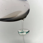 Clear, glassy texture of DAMDAM Ume Plum Firming Serum dripping from a spoon