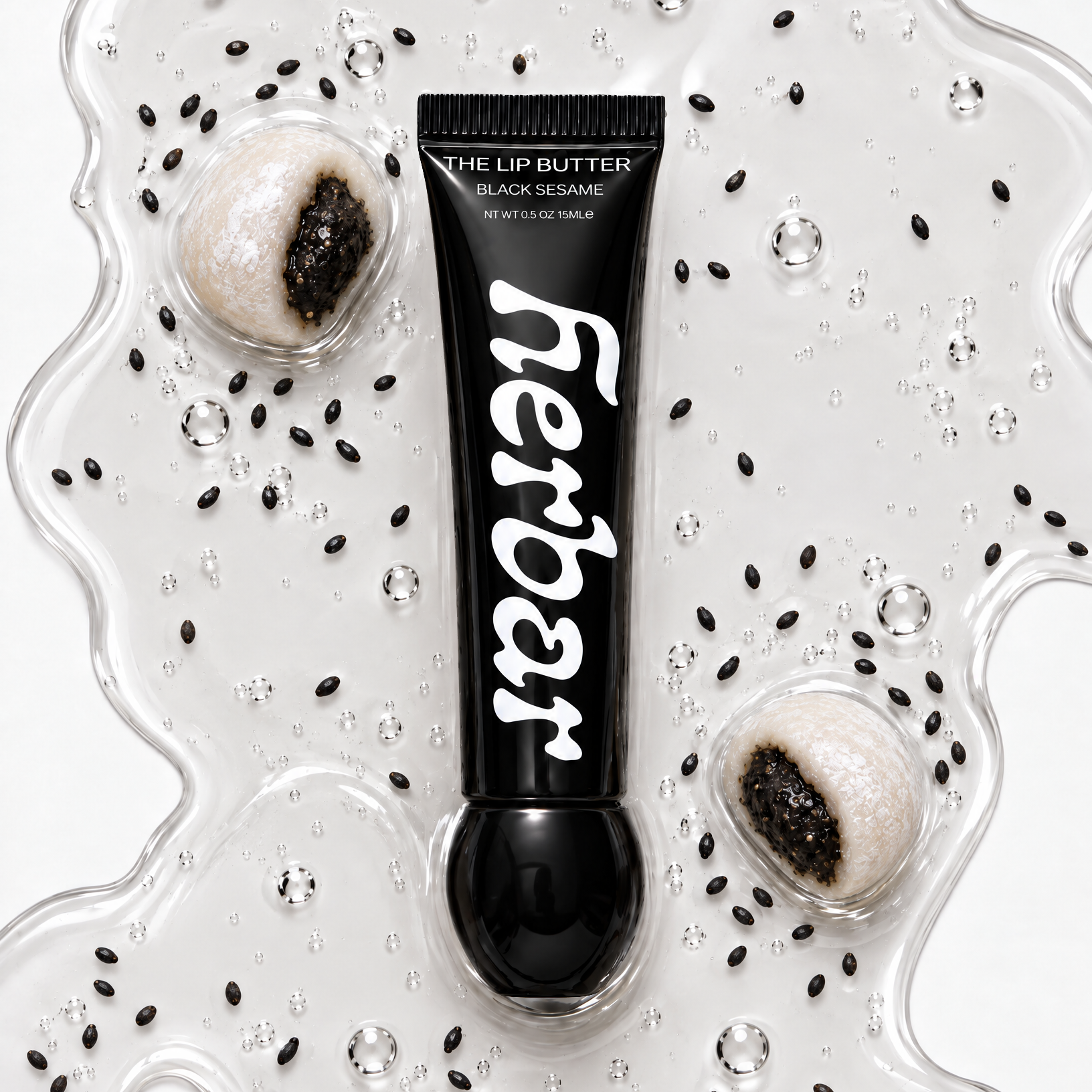 Herbar The Lip Butter Black Sesame tube on a clear buttery texture swatch scattered with sesame seeds