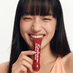 Smiling model applying Herbar The Lip Butter Jujube to her lips