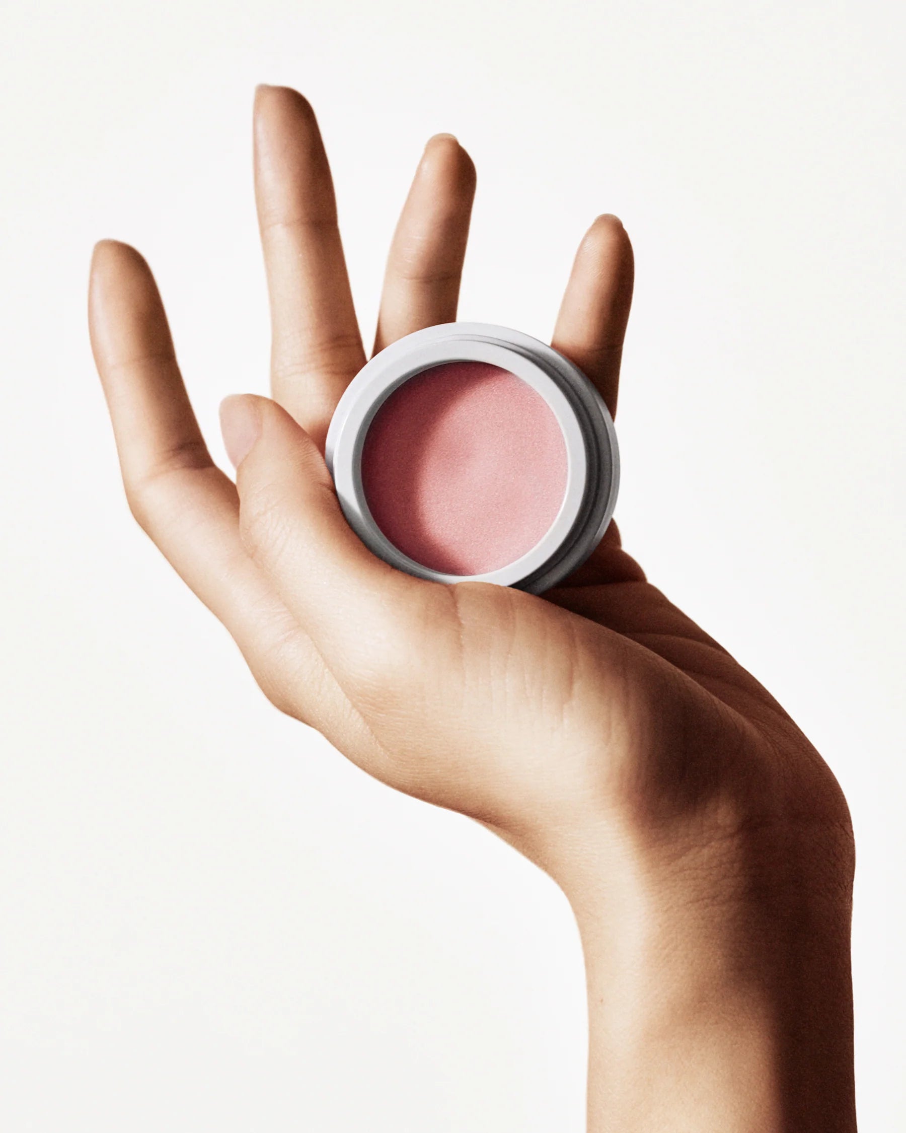 Hand holding a jar of Manasi 7 Strobelighter Sunsubiro organic cream highlighter