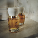 Two Porcelain No 1 Osmanth eau de parfum bottles with white porcelain caps on a stone mantelpiece