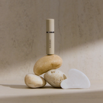 RAESO Golden Nectar Cleanser mini balanced on natural stones beside the white gua sha