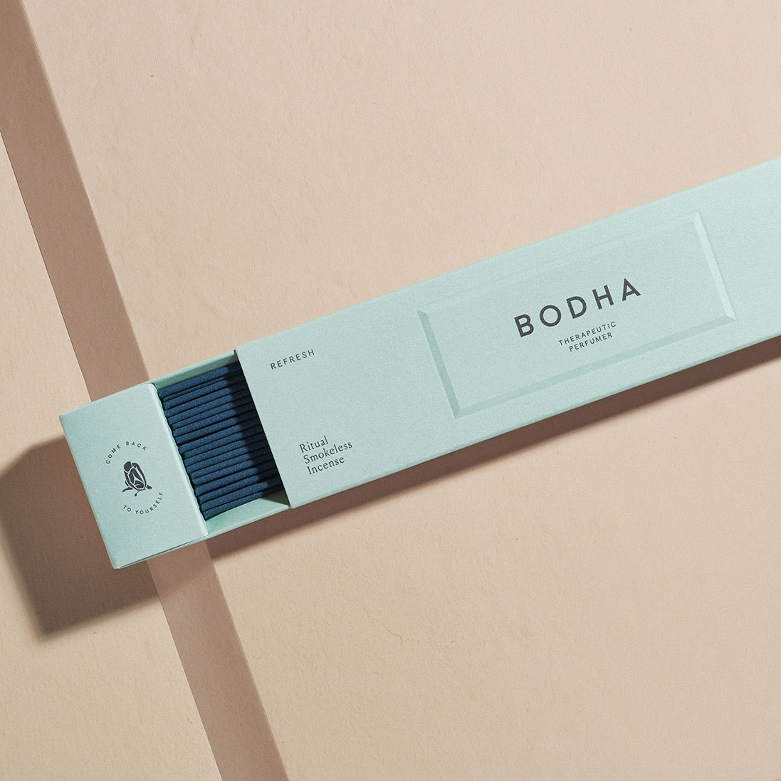 Bodha incense box on a pink surface, partially open revealing sticks inside